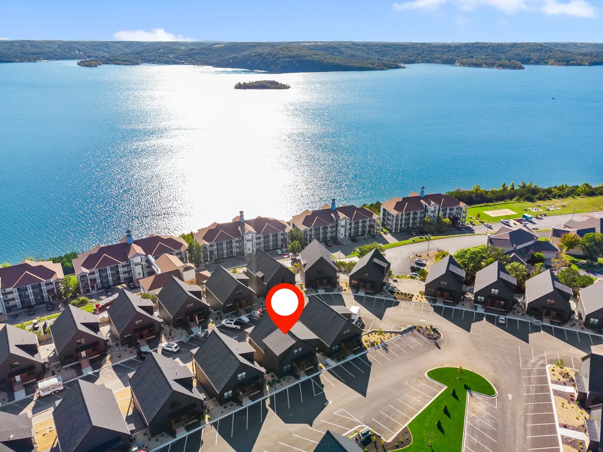 A scenic exterior view featuring a tranquil lake, an island, nearby residential buildings, and a parking area. The natural surroundings evoke a sense of adventure and exploration, suggesting opportunities for nature walks and outdoor activities.