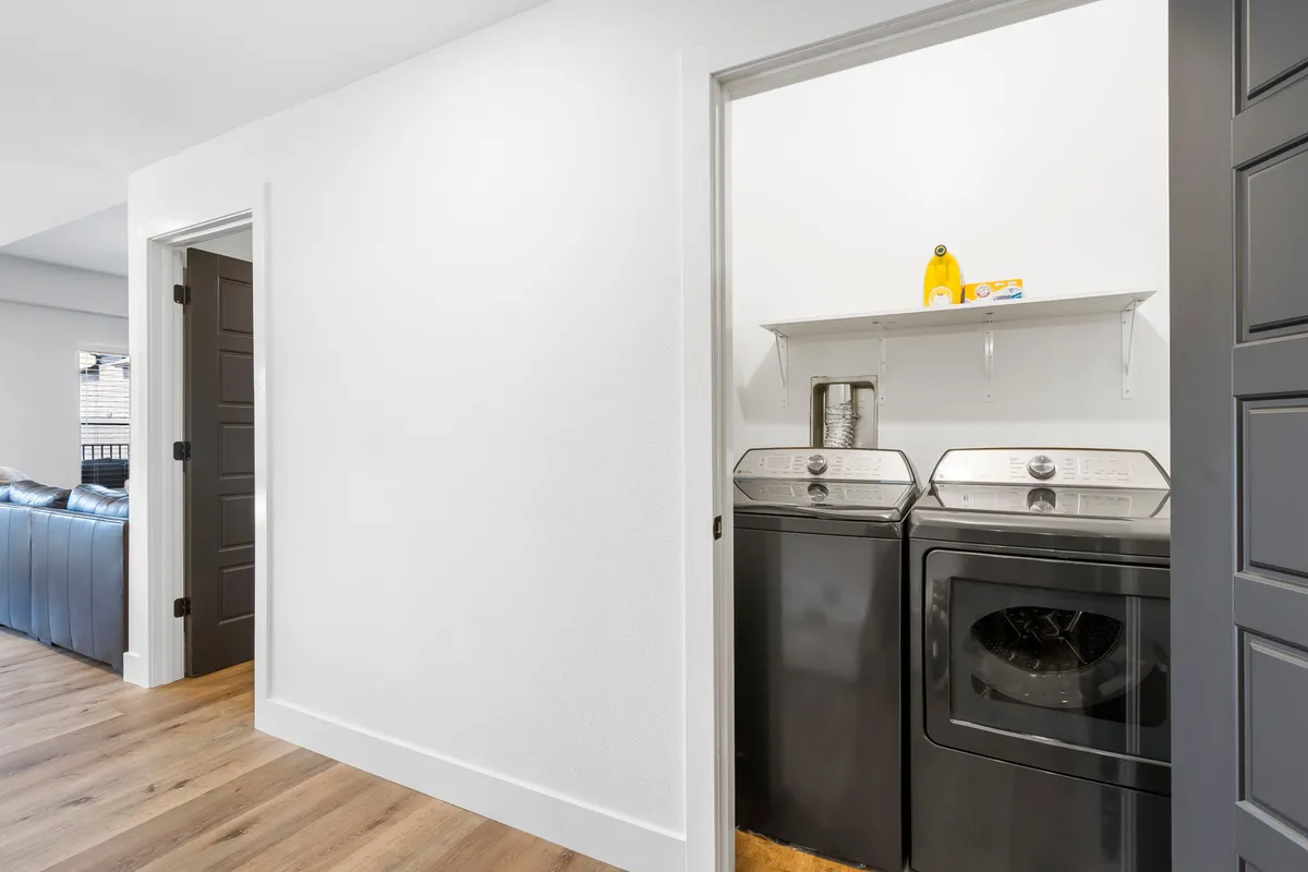 This image features a modern laundry area with a washing machine, dryer, and laundry detergent neatly organized. The scene is clean and efficient, emphasizing the availability of a private laundry facility and upholding standards of cleanliness.