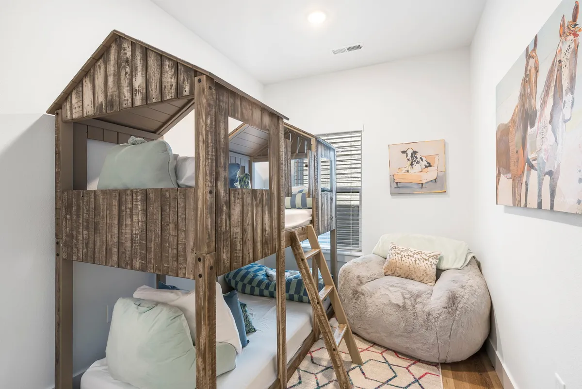 A playful bunk room featuring a lofted bunk bed, a comfortable bean bag chair for lounging or reading, and colorful artwork that adds a sense of fun. The setting is perfect for kids or young-at-heart guests seeking a personal space to rest or play.