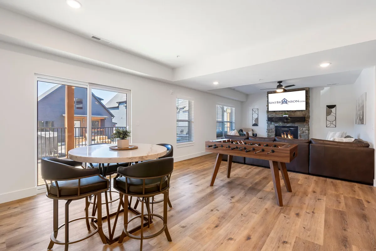 An interior view of a friendly and relaxed common area showcasing a foosball table, dining table, fireplace, and comfortable sofa seating. The atmosphere encourages playful competition, shared meals, and easygoing conversation.
