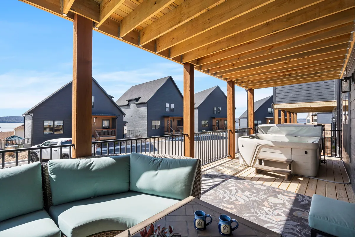 An outdoor patio featuring a private hot tub and comfortable seating, with scenic views of neighboring houses. The space is designed for relaxation, offering a seamless transition from indoor fun to outdoor unwinding.